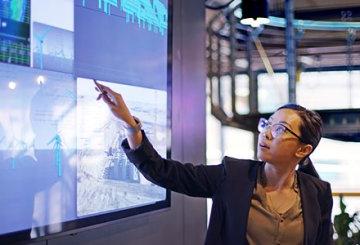 Woman pointing to large digital screen of data