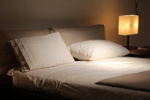 Pillows on a Bed in Dark Room with lamp light.